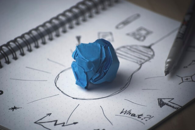 Ideenskizze mit Stift und blauem Papierknäuel