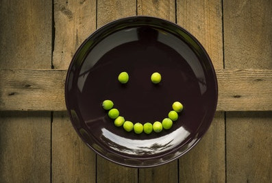 Smiley aus Erbsen auf einem Teiller