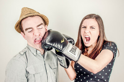 Humoristisches Bild einer jungen Frau mit Boxhandschuhen, die einen Mann boxt