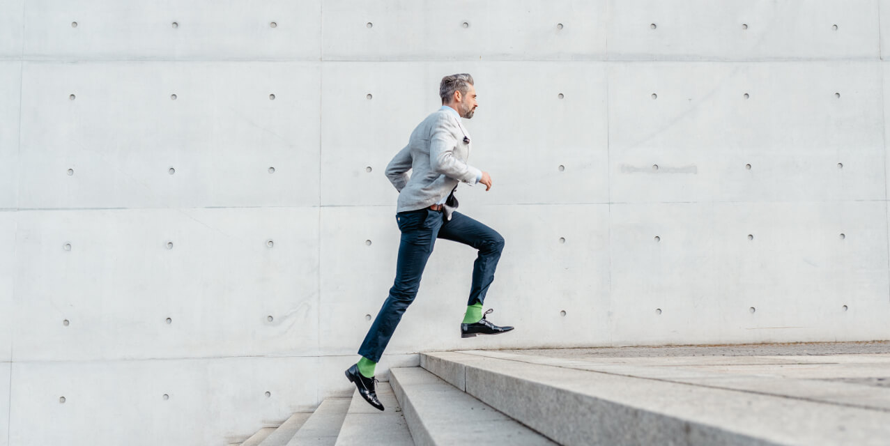 Business-Mann im hippen Anzug rennt die Treppe hoch