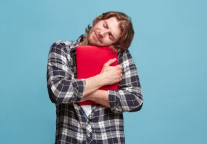 Junger Mann umarmt einen Laptop, weil er seinen Job so liebt - so funktioniert internes Employer Branding