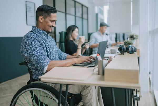 Ein Rollstuhlfahrer bei der Arbeit im Büro