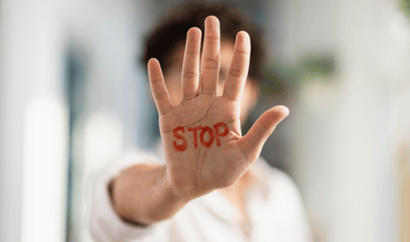 Mitarbeiter streckt Hand mit Stop-Schrift in die Kamera