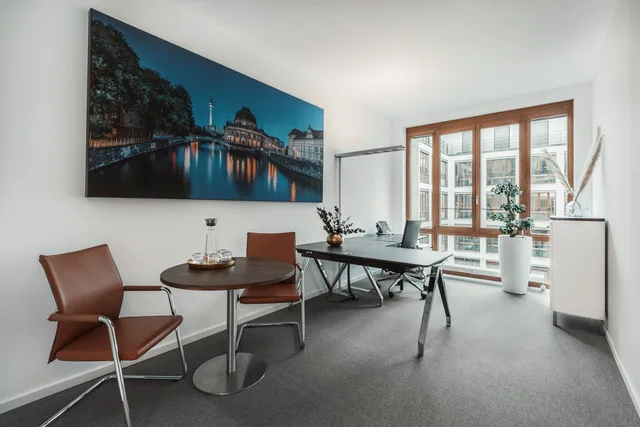 Modernes Bürozimmer mit großem Stadtpanorama-Wandbild, Besprechungstisch, Schreibtisch und Fensterfront.